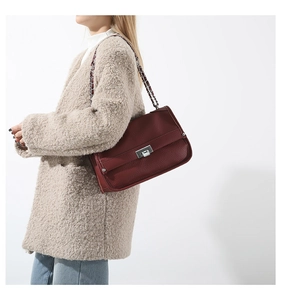 Close-up of the dark burgundy pebbled leather texture and silver buckle on messenger bag