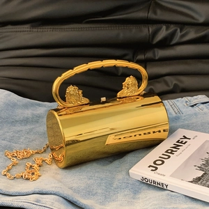 Golden cylindrical acrylic evening clutch bag with lion head carvings and metal chain strap