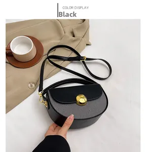 Detail of black leather and stripe fabric saddle bag with a golden round buckle