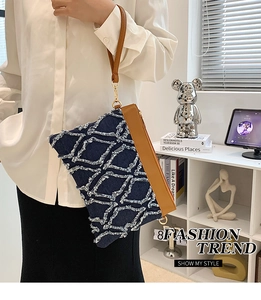 Détail d'une pochette en jean bleu avec motifs losanges à franges et bracelet en cuir
