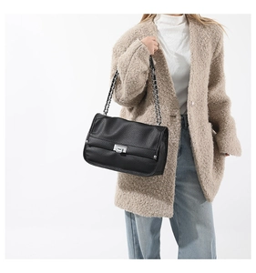 Detail of lychee pattern leather messenger bag with silver metal swivel lock and chain strap