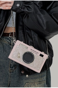 Dettaglio della borsa a tracolla rosa a forma di fotocamera con strass bianchi