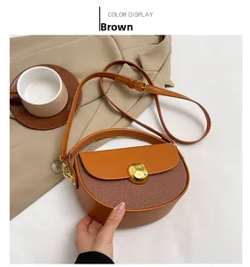 Detailed shot of brown semicircular leather bag with gold buckle and striped fabric