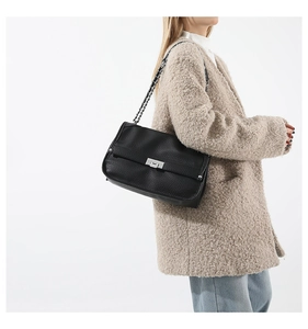 Close-up of black lychee leather messenger bag with silver hardware on a female model