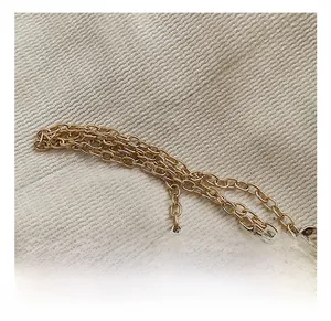 Detailed close-up of premium golden metal chain strap on textured beige fabric background