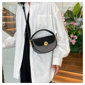 Detail of a half-moon shoulder bag with a gold buckle worn with a white shirt