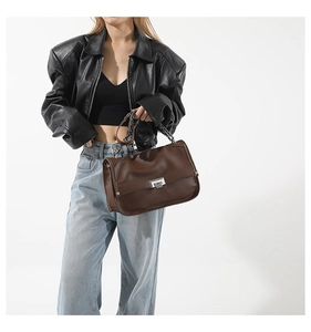 Detail of dark brown pebble leather bag with silver metal lock and chain strap