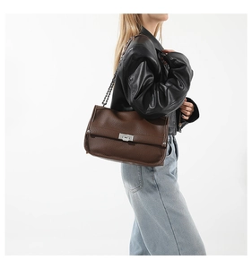 Detail of dark brown leather messenger bag with silver twist lock and metal chain strap