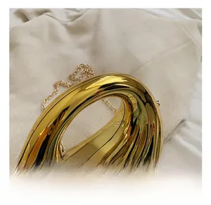 Detail of creative gold metallic evening bag with sleek handle and shiny mirror finish