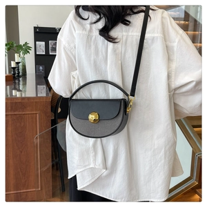 Detail of half-moon crossbody bag with gold textured buckle and black-grey panel design