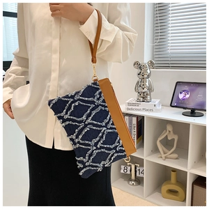 Détail du sac à bandoulière en jean bleu avec texture matelassée et anse en cuir