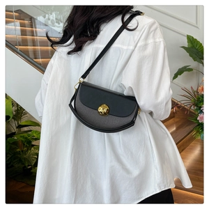 Minimalist half-moon saddle bag with gold ball clasp shown on a model against white shirt