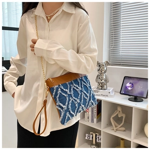 Détail du sac bandoulière en denim avec texture losange à franges et bordure en cuir brun