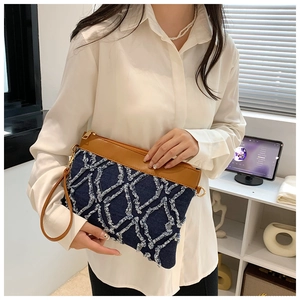 Détail de la pochette en denim bleu et cuir marron avec texture matelassée à franges