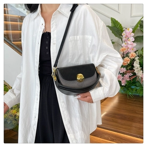 Detail of black semicircular bag with gold spherical metal lock and leather texture