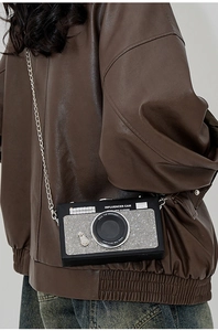 Dettaglio della borsa a tracolla a forma di fotocamera con strass e catena in metallo