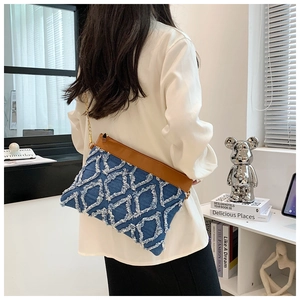 Vue détaillée du sac bandoulière en denim et cuir avec texture matelassée et effilochée