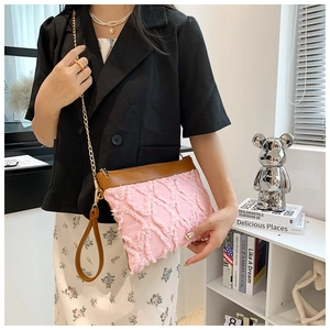Détail du sac bandoulière en tweed rose avec bordure en cuir marron et chaîne dorée