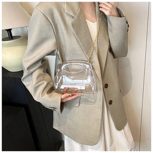 Close-up of transparent trapezoid acrylic bag with golden metal chain strap on model