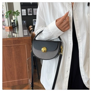 On-model shot of a half-round saddle bag in black and grey with gold metal buckle
