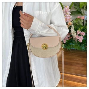 Detail of a half-moon shoulder bag with beige leather, straw weave, and gold buckle detail