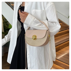 Detail of beige semicircular bag with gold cat clasp and woven texture paneling