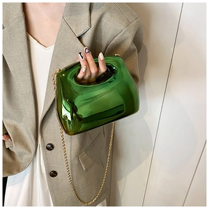 Detail of emerald green metallic acrylic handbag with gold chain strap on model