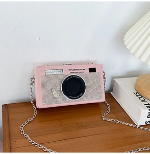 Dettaglio borsa rosa a forma di fotocamera con strass luccicanti e catena in metallo