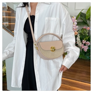 Detail of beige half-moon bag featuring woven leather texture and golden metal lock