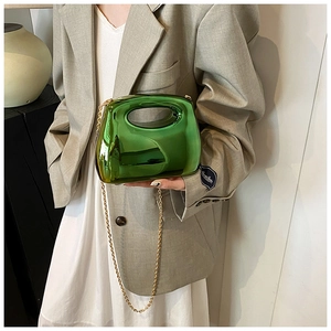 Green acrylic clutch bag with metallic finish and gold chain strap on female model