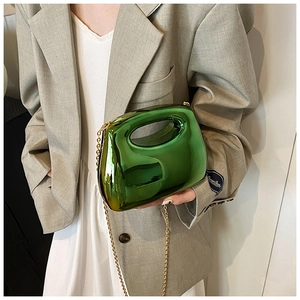 Green acrylic evening bag with mirror finish and gold chain strap shown on a model