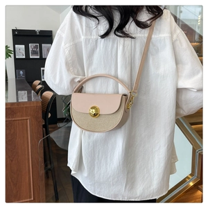 Detail of beige semicircular crossbody bag with woven texture and gold circular buckle