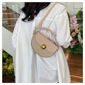 Detail of a chic half-moon straw and leather crossbody bag with a gold metal lock
