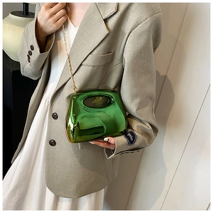 Detail of emerald green acrylic clutch with mirror finish and gold chain on elegant outfit