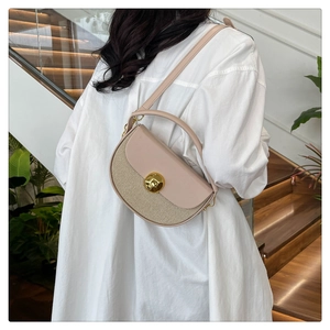 Detail of beige saddle bag with woven texture, golden ring clasp and top handle on a model