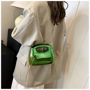 Chic green metallic acrylic crossbody bag with gold chain strap worn over beige blazer