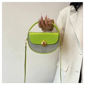 Detail of green and striped semicircular handbag with a gold sphere buckle and strap