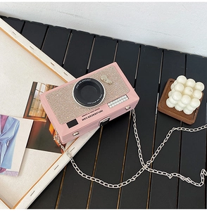 Dettaglio della borsa a tracolla rosa a forma di fotocamera con glitter e catena
