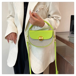 Detail of green half-moon bag with woven base, gold lock, and Lucky Girl ribbon handle