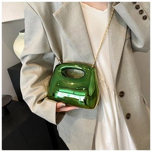 Detail of green metallic mirror finish acrylic clutch with gold chain strap on model