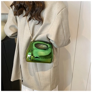Model showing metallic green acrylic hard-shell clutch bag with gold chain strap