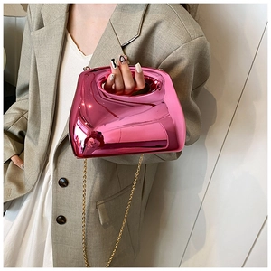 Close-up of metallic pink acrylic handbag with circular handle and gold chain strap