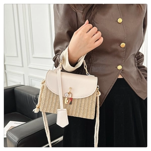Dettaglio borsa in paglia intrecciata con patta in pelle crema e lucchetto in metallo dorato
