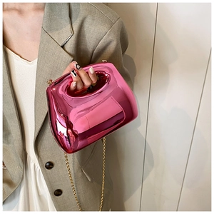 Detail of metallic pink acrylic handbag featuring a gold chain strap and structured handle