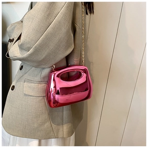 Detail of trendy metallic hot pink acrylic clutch with gold chain strap and hollow handle