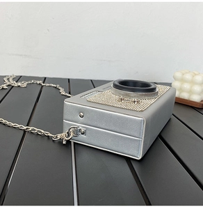 Dettaglio della borsa a tracolla argentata a forma di fotocamera con strass e catena