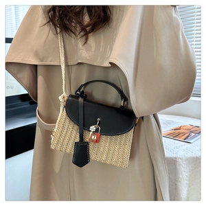 Dettaglio borsa in paglia intrecciata con patta in pelle nera e tracolla in corda di cotone
