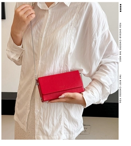Detail shot of a minimalist red rectangular crossbody bag with silver chain strap