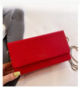 Detail of red square chain bag with silver strap and embossed text on flap closure
