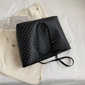 Detailansicht der grossen schwarzen Shopper Tasche mit Muster auf hellem Hintergrund.